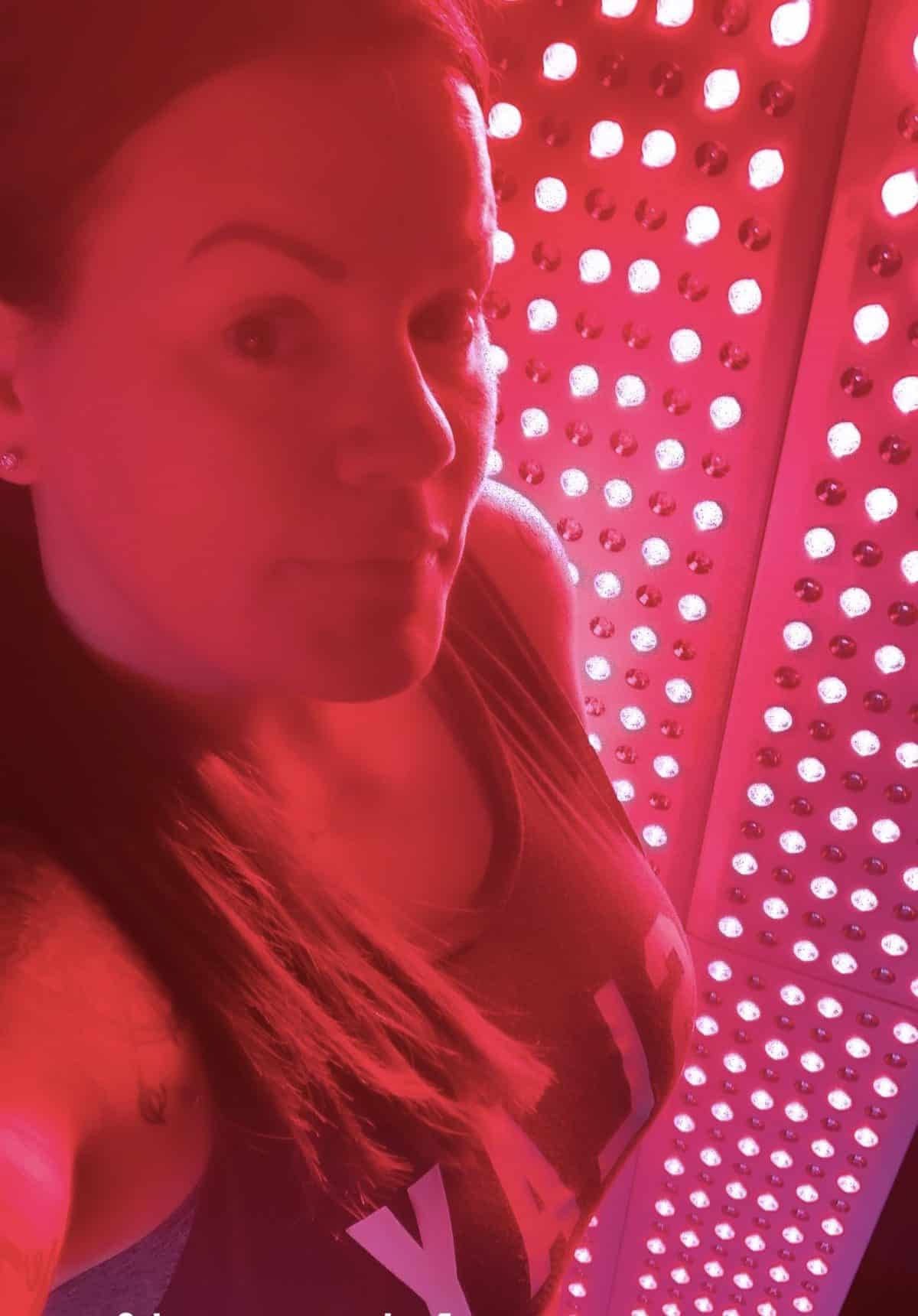 Woman standing in front of a Joovv Elite Red Light Therapy Unit