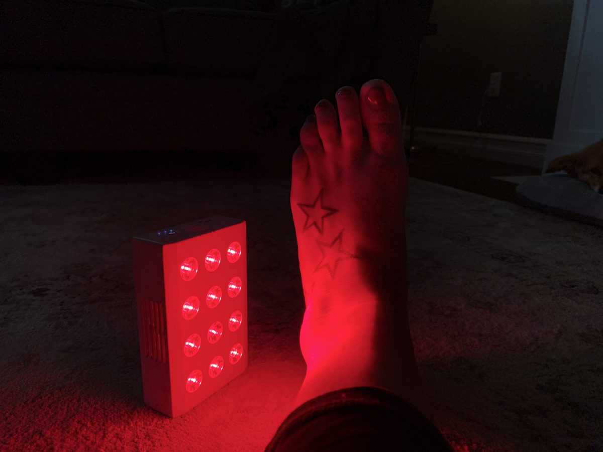 Mini red light therapy unit on a woman ankle