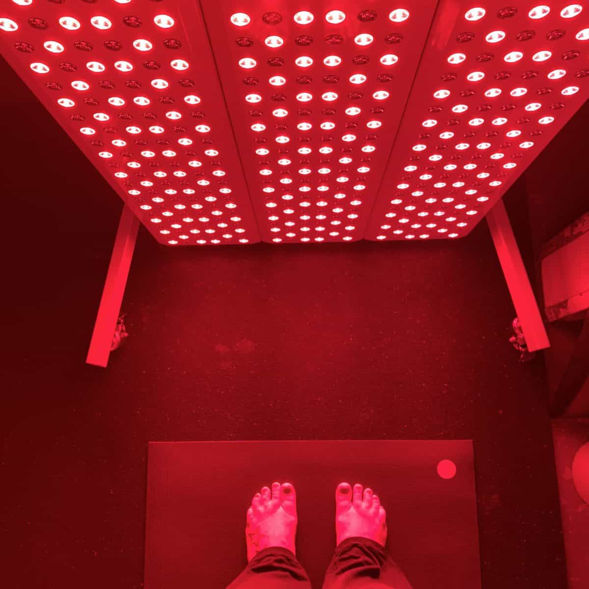 Women standing on a yoga mat in front of a red light therapy unit