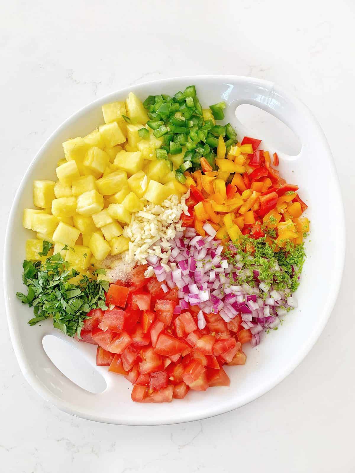 White serving bowl, full of fresh fruits and vegetables for Pineapple Salsa 