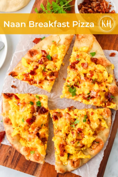 naan bread pizza on a wood cutting board, topped with scrambled eggs, cheese, and bacon