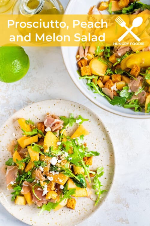a fresh summer salad of prosciutto, peaches, melon, walnuts, croutons, feta, and arugula on a white plate