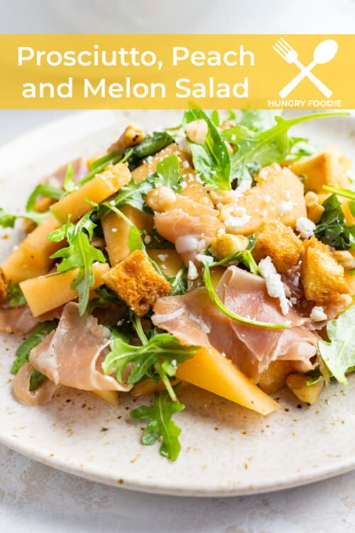 a fresh summer salad of prosciutto, peaches, melon, walnuts, croutons, feta, and arugula on a white plate