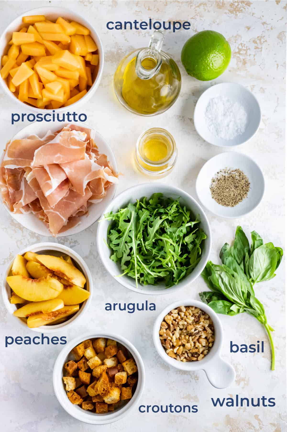 Spread of salad ingredients - prosciutto, peaches, arugula, cantaloupe, croutons, basil, walnuts