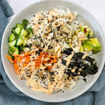 Ingredients for a california sushi roll all piled in a bowl - crab, rice, carrots, avocado, cucumber