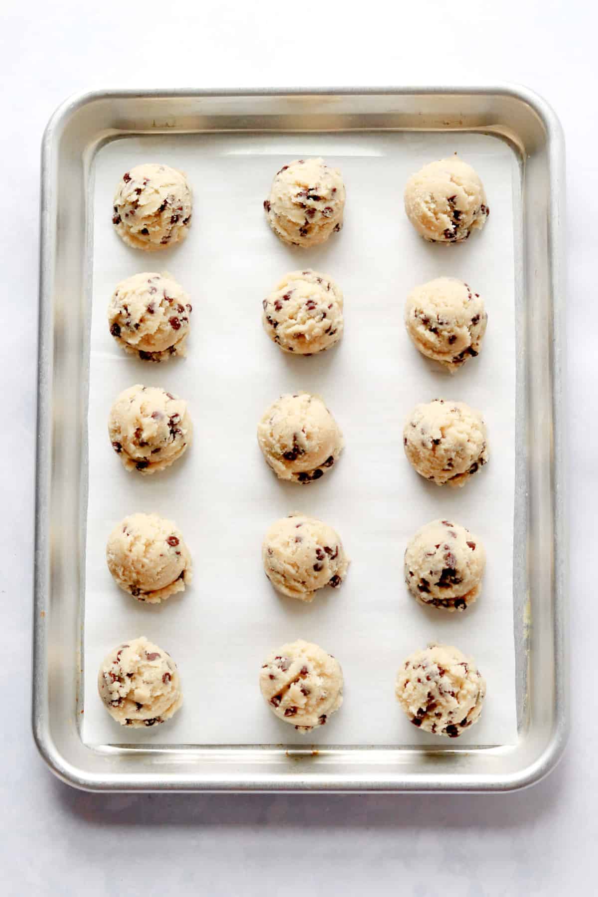 A rimmed baking sheet lined with parchment paper and topped with keto chocolate chip cookie dough bites