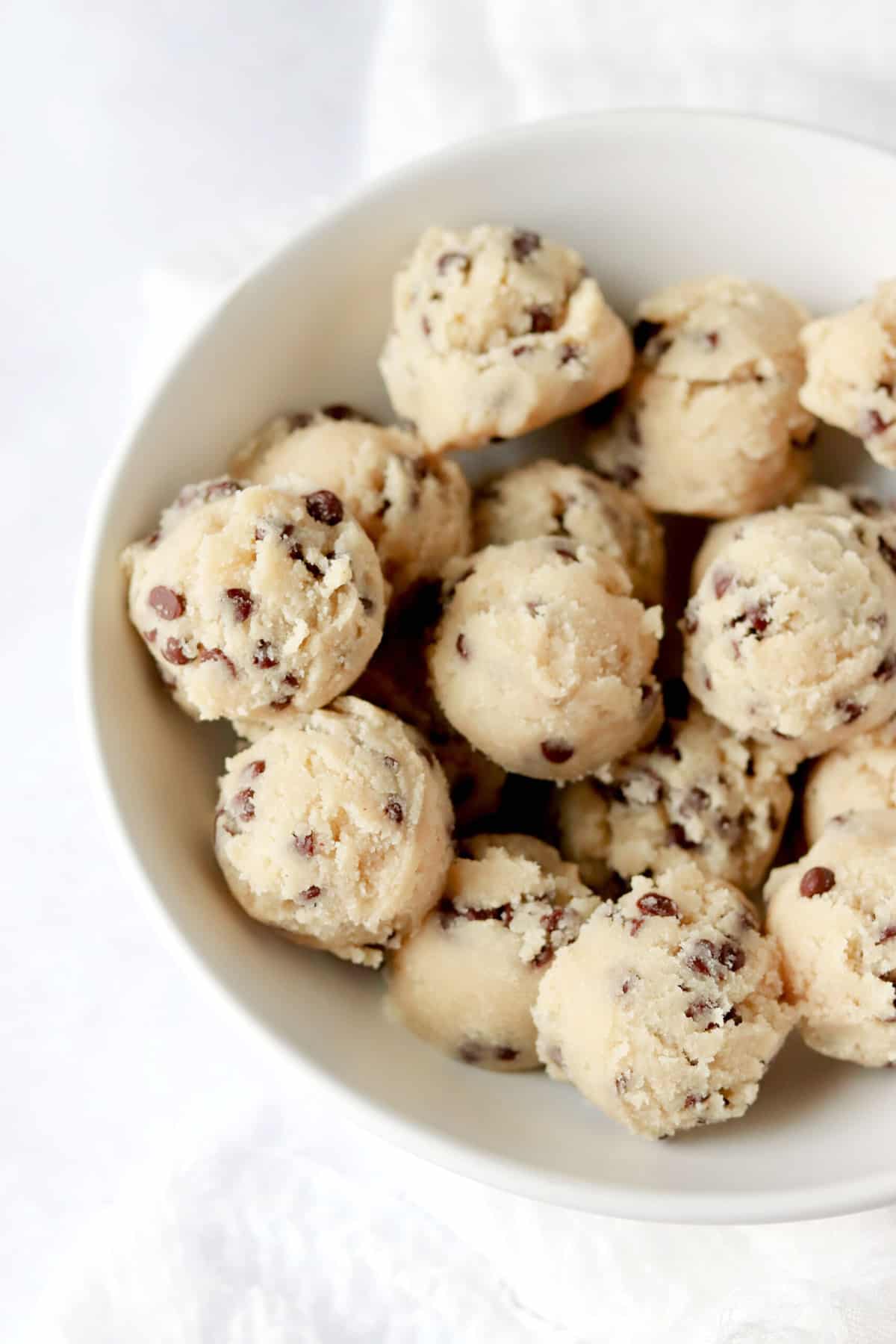 a white bowl full of chocolate chip cookie dough bites