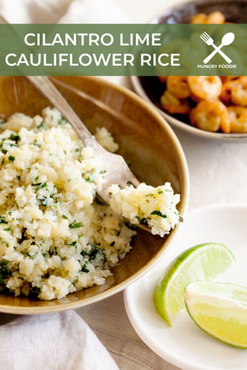 wooden bowl full of cilantro lime cauliflower rice, garnished with fresh lime wedges