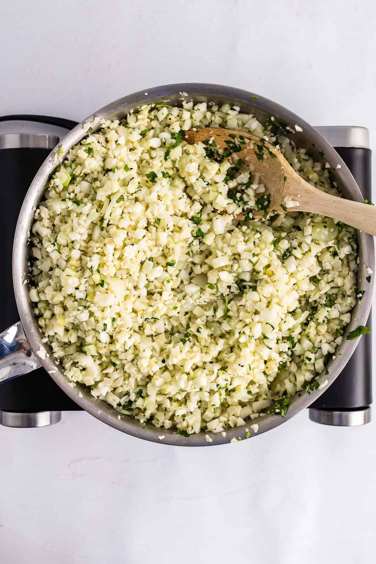 skillet with onion, garlic, cauliflower, lime zest, cilantro, and butter