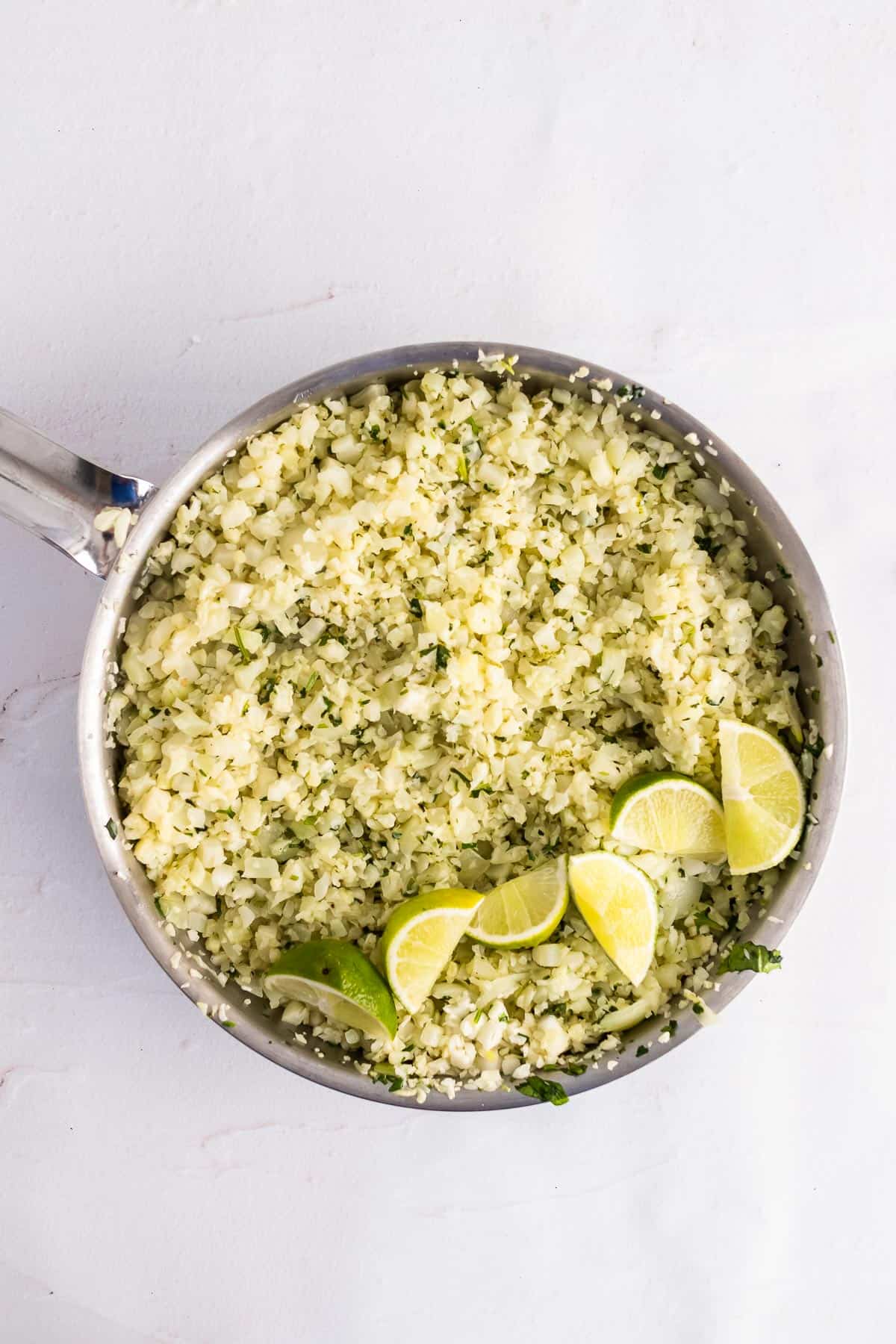 skillet with onion, garlic, cauliflower, lime zest, cilantro, and butter