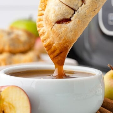 Air Fryer Apple Hand Pies Being Dipped into Caramel Sauce