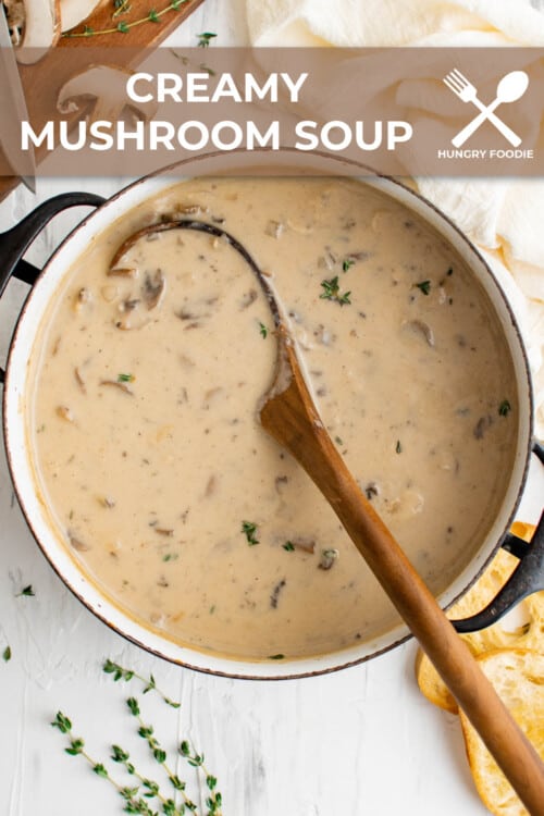 a pot of cream of mushrooms soup, with a wooden ladle, served with bread