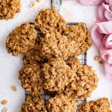 a pile of no bake cookies on a cooling rack, surrounded by a pink towel and ingredients