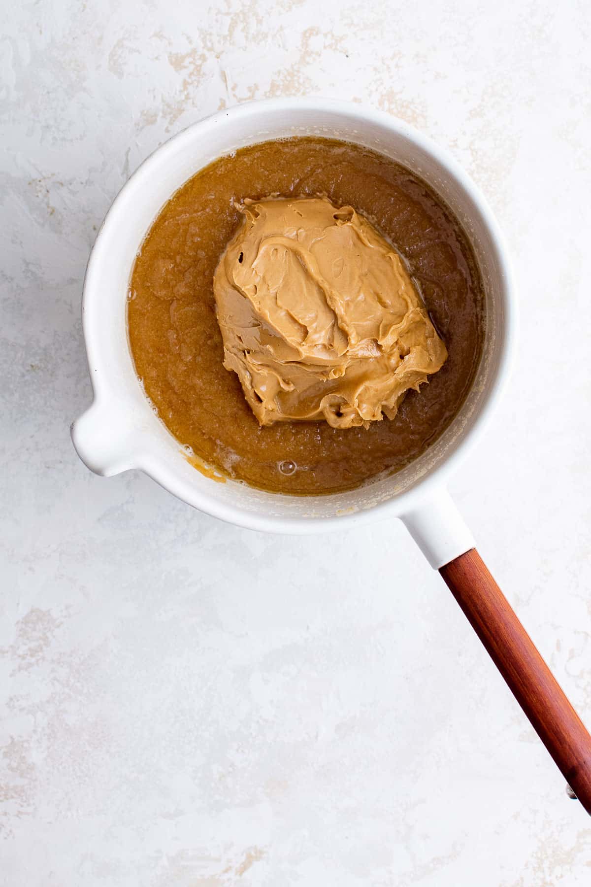 a sauce pan with melted butter, white sugar, brown sugar and peanut butter in it