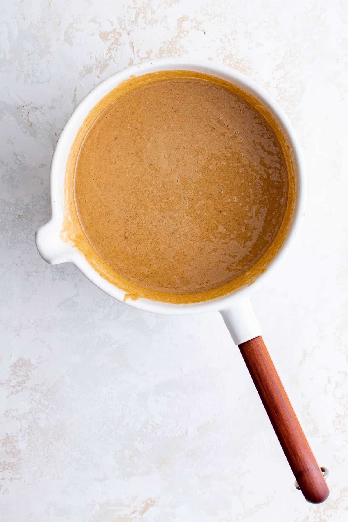 a sauce pan with melted butter, white sugar, brown sugar and peanut butter in it