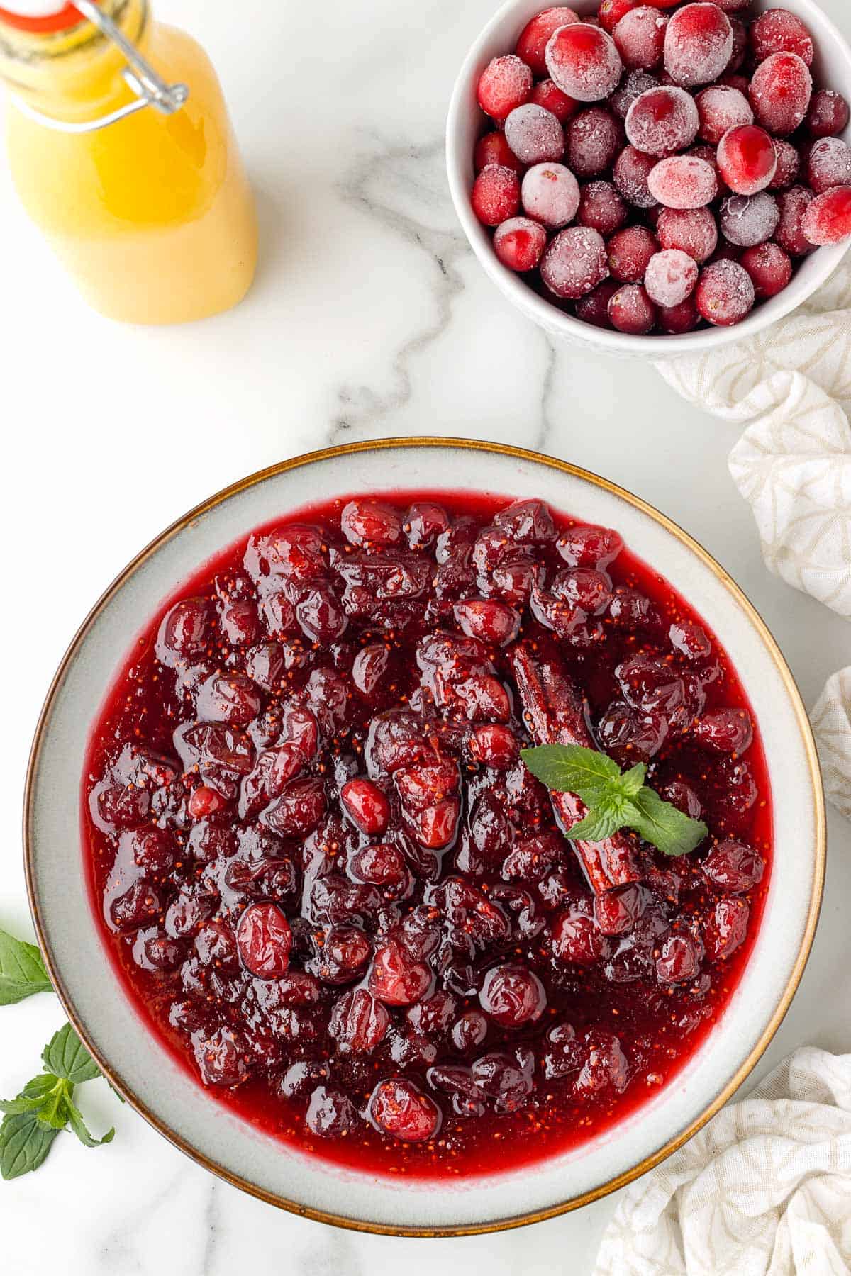 a bowl of homemade cranberry sauce, garnished with fresh mint and cinnamon