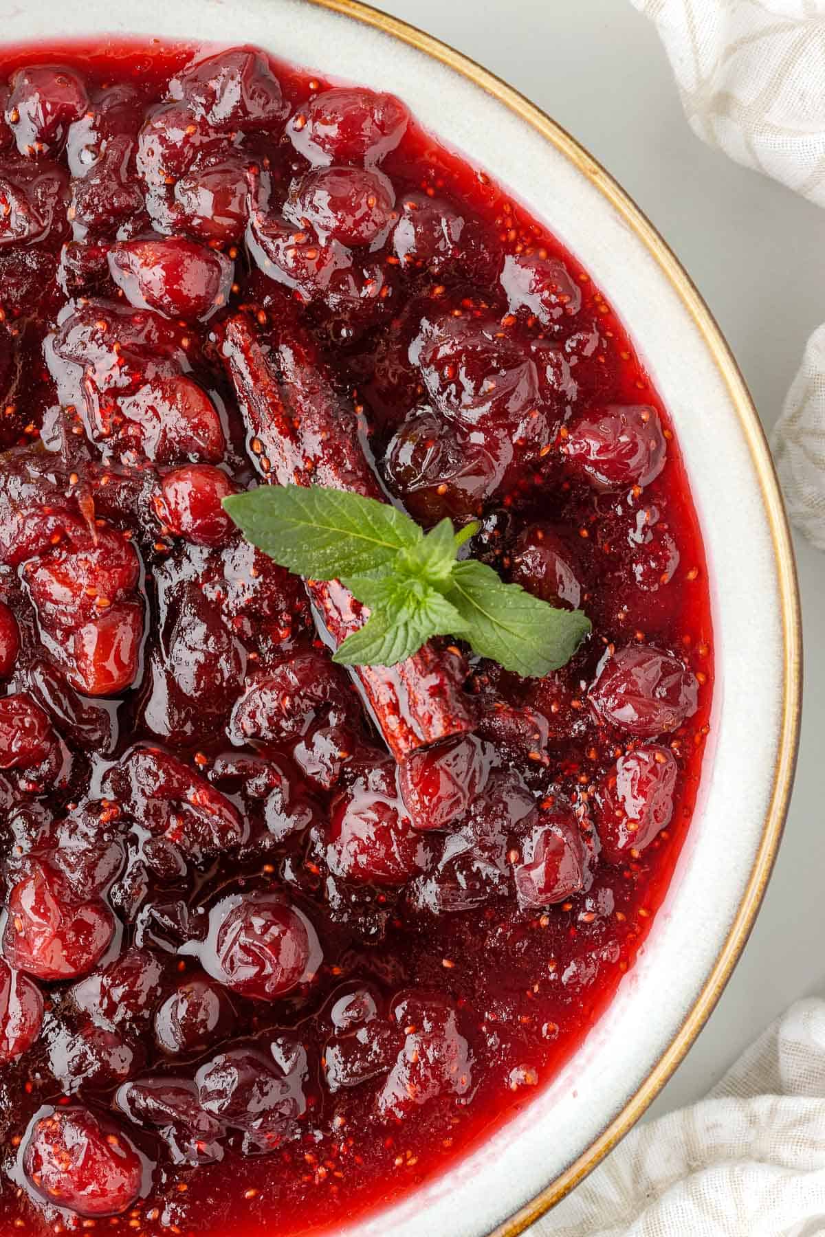 a bowl of homemade cranberry sauce, garnished with fresh mint and cinnamon