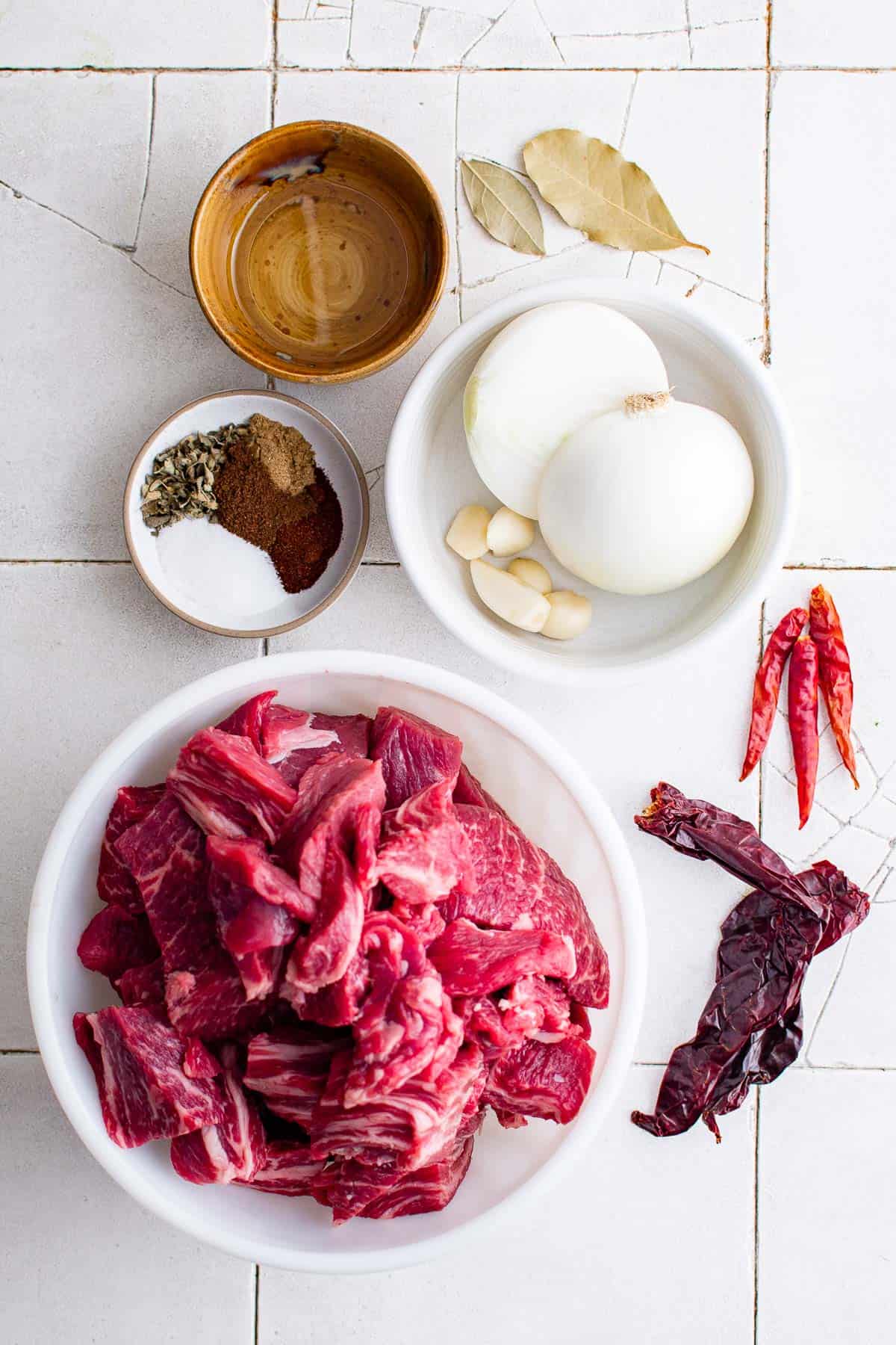 ingredients to make birria - chuck roast peppers, onions, seasoning, water