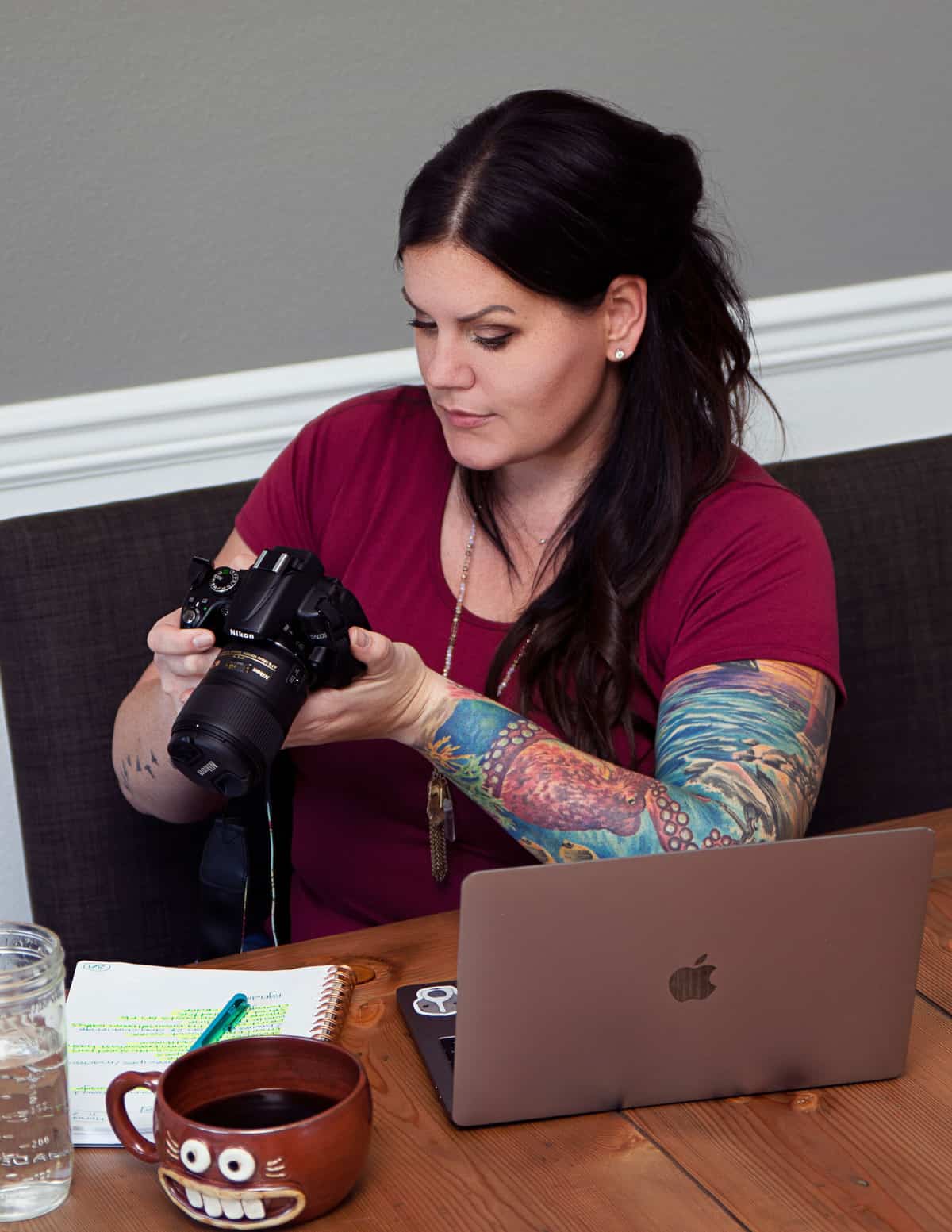 woman with long dark hair, wearing a red shirt, looking at pictures on her camera