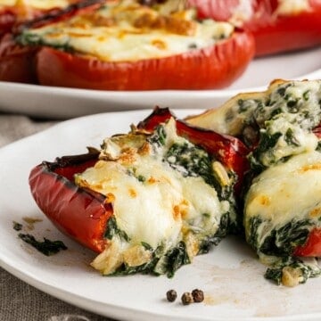 red bell peppers stuffed with cheese and spinach, served on a white plate