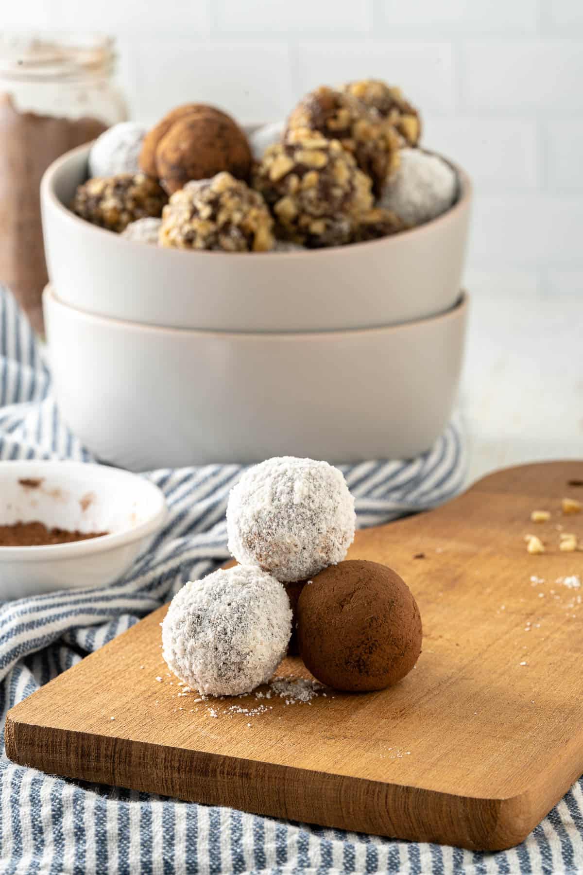 a bowl of assorted chocolate truffles, covered with cocoa powder, coconut, and walnuts