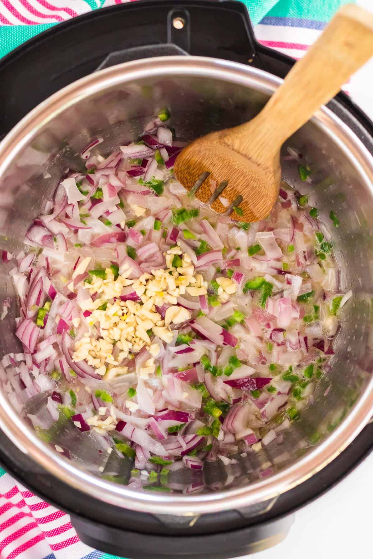 an instant pot with red onion garlic, and jalapeños.