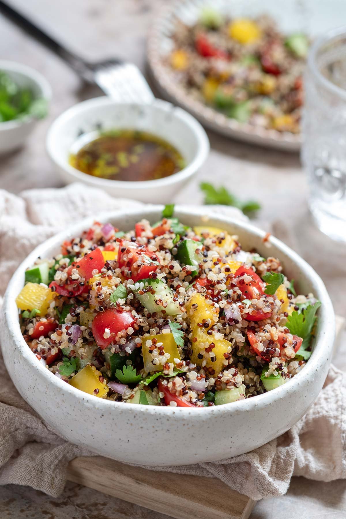 a quinoa salad with tomatoes, cucumber, red onion, mandarins, bell peppers and parsley.