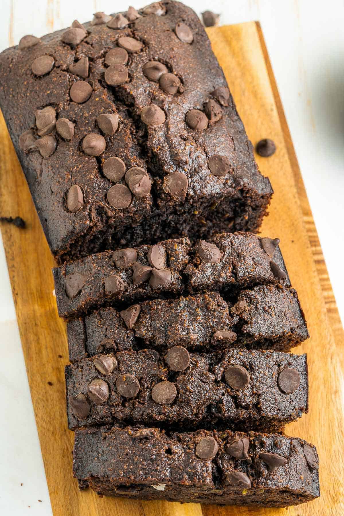 A fresh load of low carb and gluten free chocolate zucchini bread sliced on a wooden cutting board. 