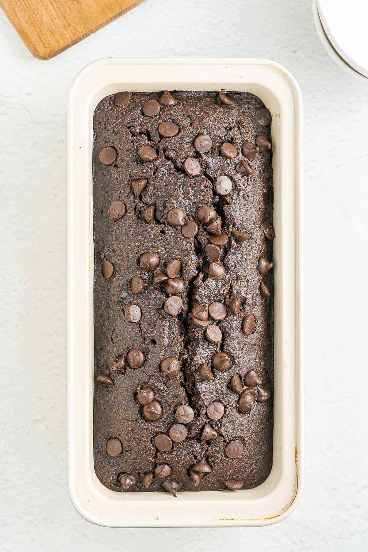 A fresh loaf of low carb and gluten free chocolate zucchini bread sliced on a wooden cutting board.