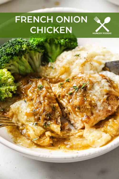 An enameled cast iron skillet with cooked chicken breasts, topped with a caramelized onion pan sauce and melty cheese.