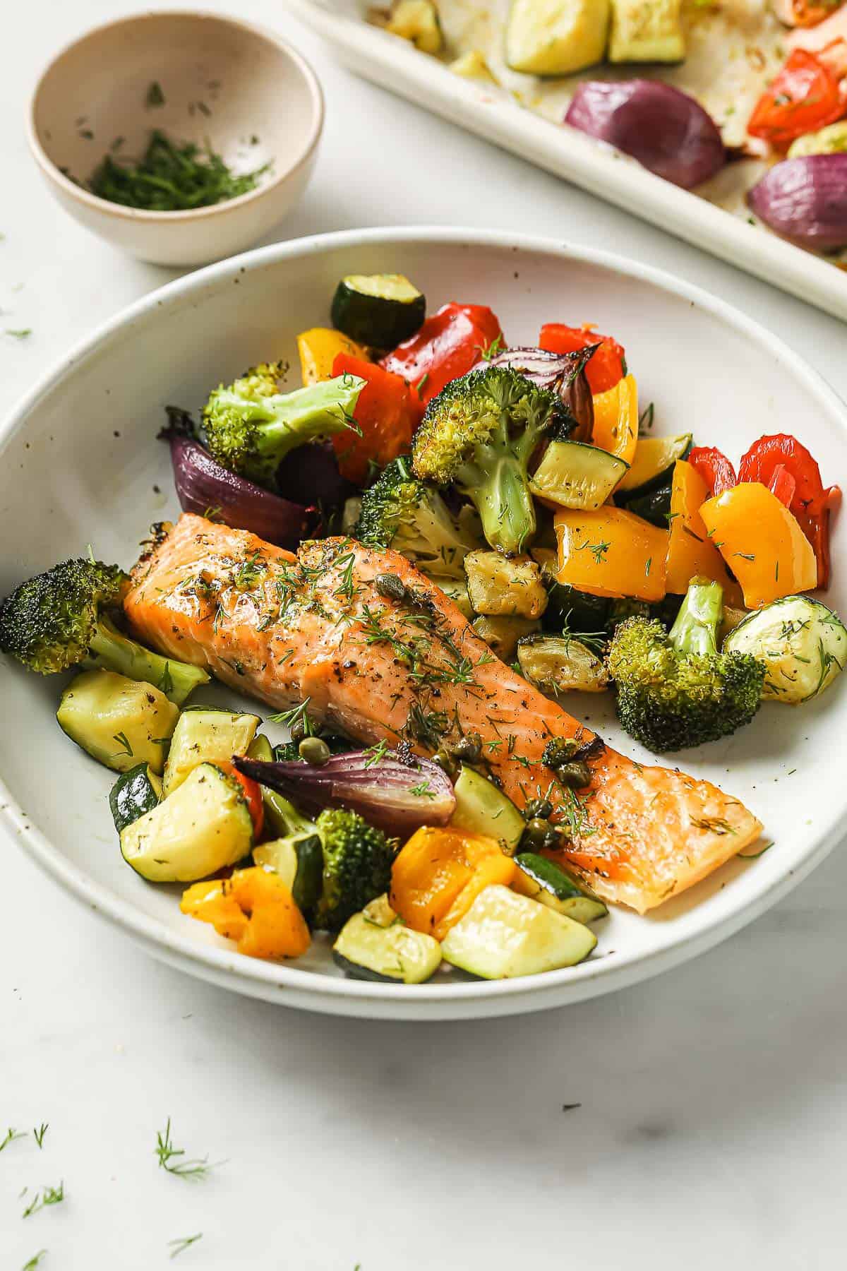 A sheet pan meal with salmon, zucchini, broccoli, red onion, peppers, capers, garlic, olive oil and spices.