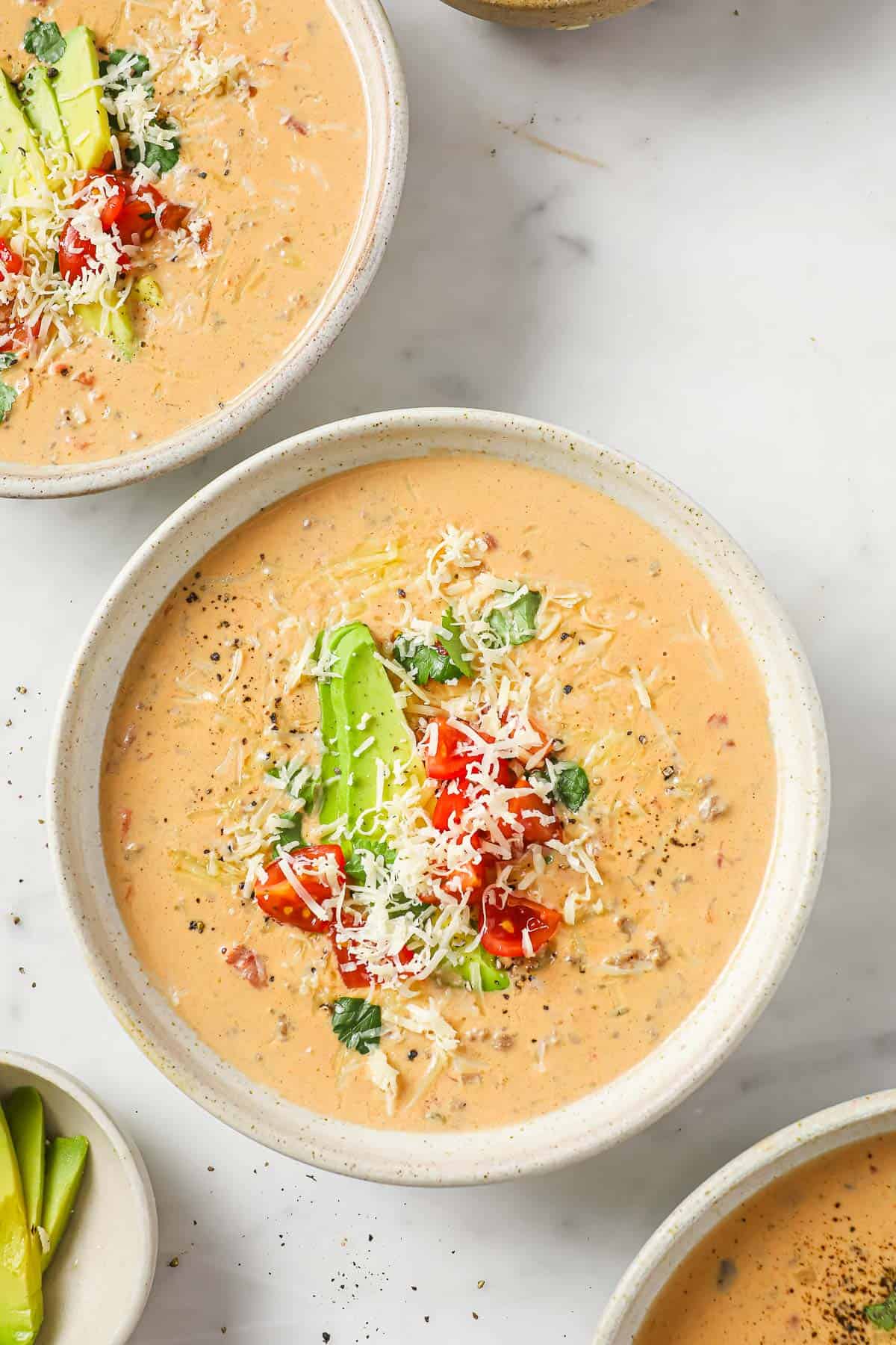 A bowl of creamy taco soup, garnished with avocado, tomatoes, cheese, and cilantro.